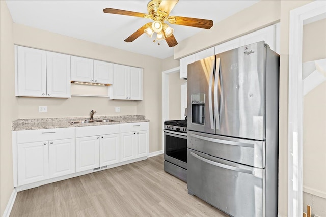 kitchen with light hardwood / wood-style floors, sink, white cabinets, stainless steel appliances, and light stone counters