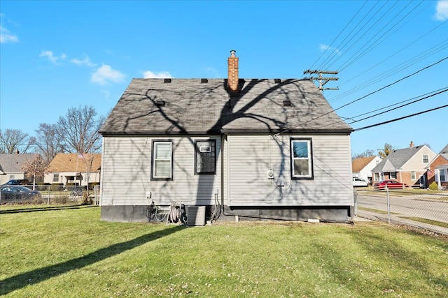 rear view of house featuring central AC unit and a yard