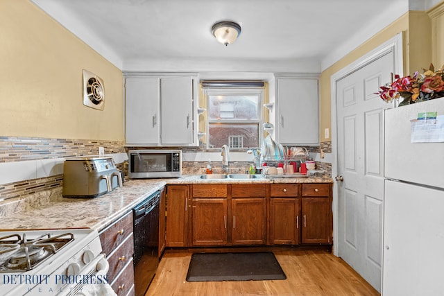 kitchen featuring dishwasher, white refrigerator, white cabinetry, and sink