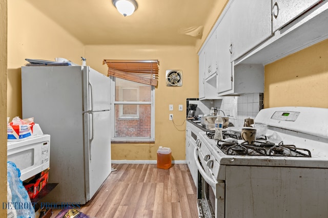 kitchen with sink, tasteful backsplash, white appliances, white cabinets, and light wood-type flooring