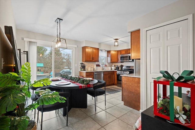 kitchen featuring sink, a healthy amount of sunlight, stainless steel appliances, decorative light fixtures, and decorative backsplash