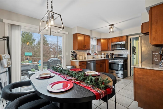 kitchen with pendant lighting, sink, decorative backsplash, light tile patterned floors, and stainless steel appliances