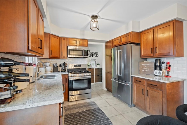 kitchen featuring light stone countertops, appliances with stainless steel finishes, backsplash, sink, and light tile patterned floors