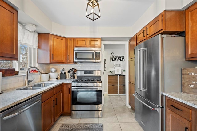 kitchen featuring decorative backsplash, light stone counters, sink, and stainless steel appliances