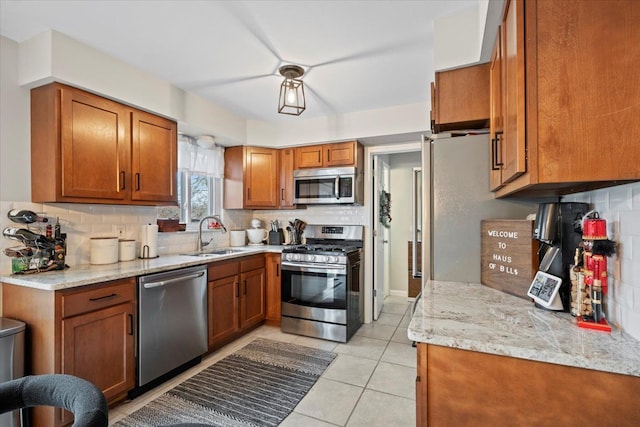 kitchen featuring light stone countertops, sink, stainless steel appliances, decorative backsplash, and light tile patterned floors