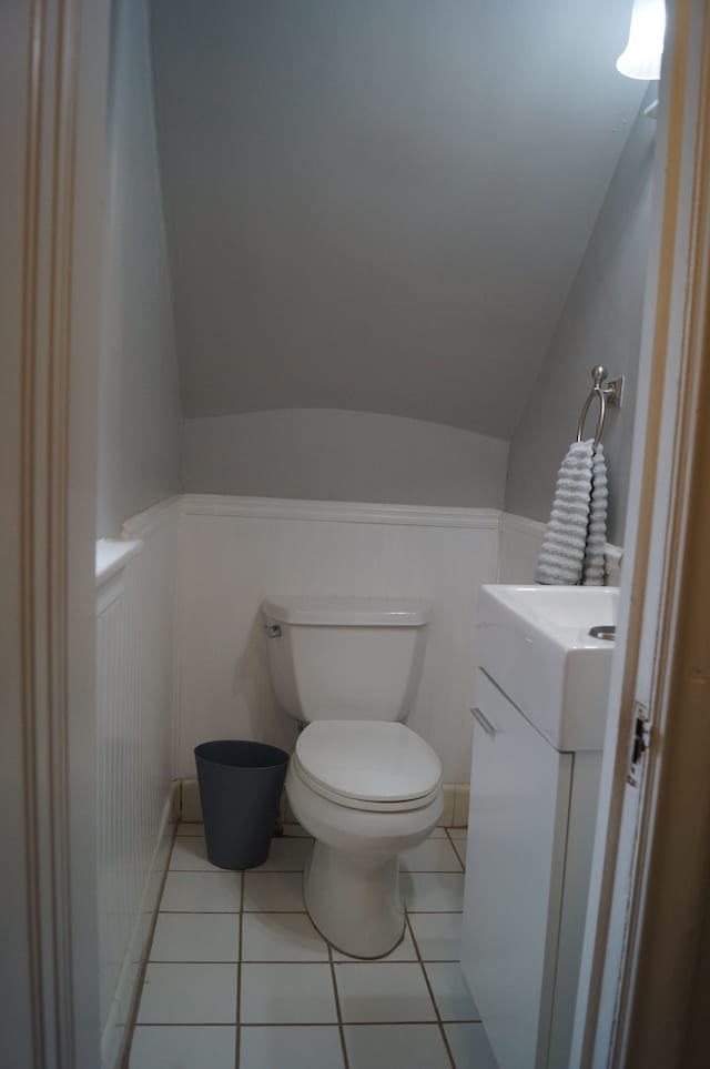 bathroom with tile patterned floors, vanity, toilet, and vaulted ceiling