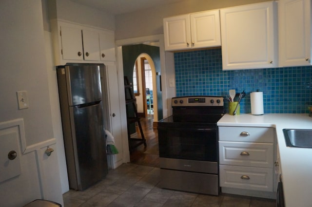 kitchen featuring decorative backsplash, white cabinets, and appliances with stainless steel finishes