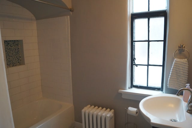 bathroom featuring shower / bathing tub combination, radiator heating unit, and sink