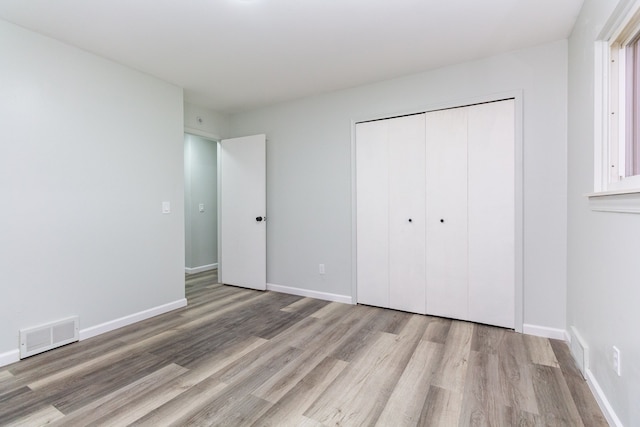 unfurnished bedroom with light wood-type flooring and a closet