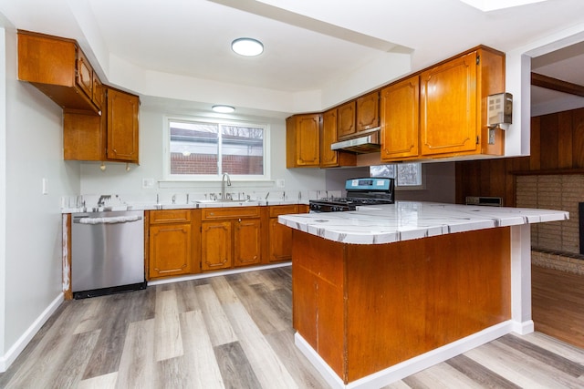 kitchen featuring black gas range, dishwasher, sink, light hardwood / wood-style flooring, and kitchen peninsula