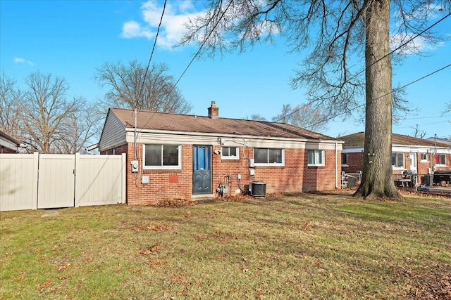 back of property with central AC unit and a yard