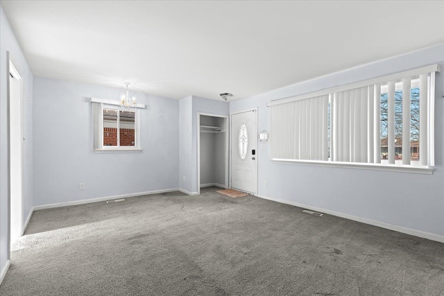 spare room with carpet floors, a notable chandelier, and a healthy amount of sunlight