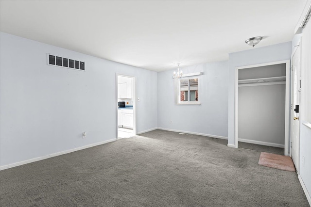 unfurnished bedroom with a closet, carpet, and a notable chandelier