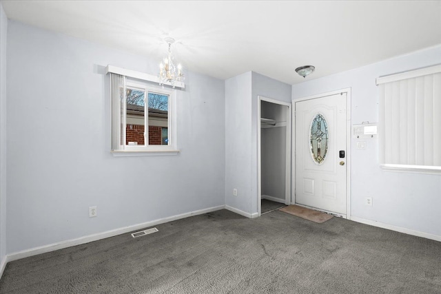 carpeted foyer with a notable chandelier