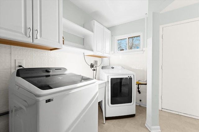 washroom with light tile patterned flooring, cabinets, and washer and dryer