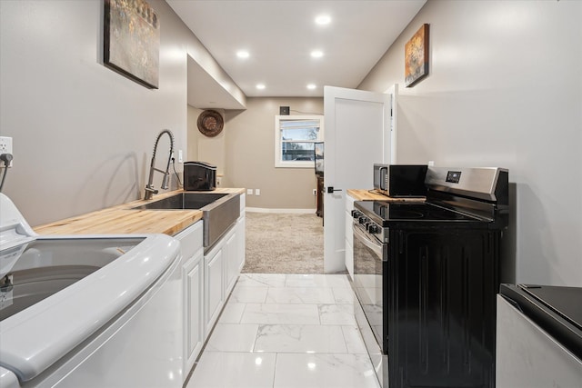 kitchen featuring light colored carpet, sink, white cabinets, stainless steel gas stove, and washer / clothes dryer