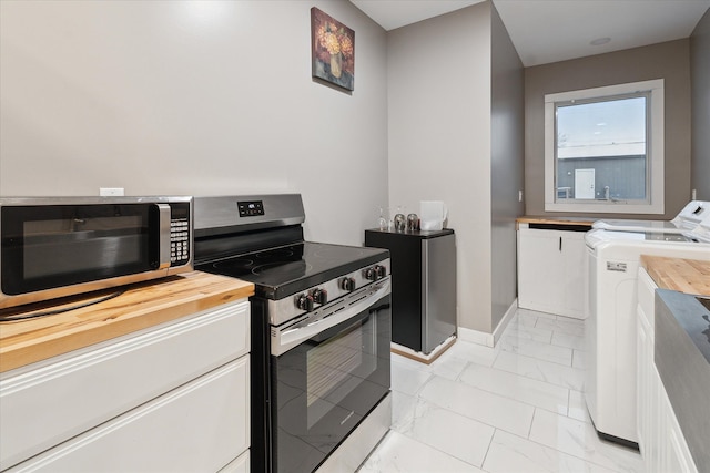 kitchen featuring washer and dryer, butcher block counters, and appliances with stainless steel finishes