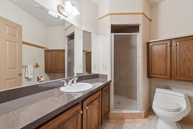 bathroom featuring toilet, vanity, tile patterned floors, and a shower with shower door