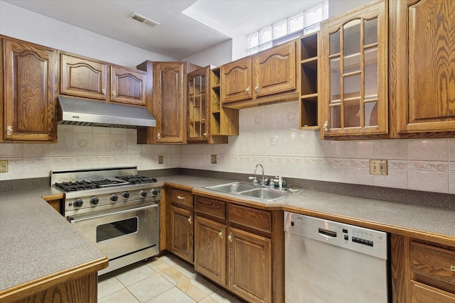 kitchen with range hood, dishwasher, sink, high end stainless steel range oven, and light tile patterned floors