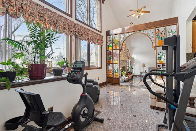 exercise room with ceiling fan and a towering ceiling