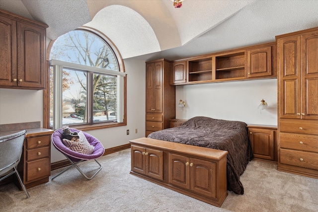 bedroom with lofted ceiling, light colored carpet, and a textured ceiling