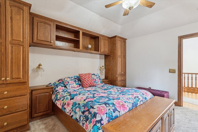 bedroom featuring light carpet, ceiling fan, and a tray ceiling