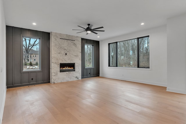 unfurnished living room with a fireplace, light hardwood / wood-style flooring, and ceiling fan