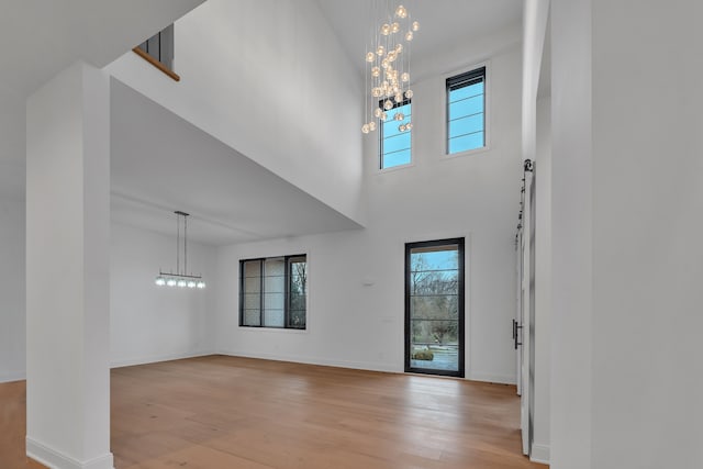 entryway featuring light hardwood / wood-style flooring, a high ceiling, and a notable chandelier