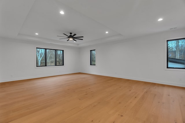 empty room featuring a tray ceiling, light hardwood / wood-style flooring, and ceiling fan