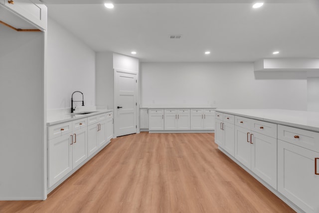 kitchen with white cabinetry, sink, and light hardwood / wood-style flooring