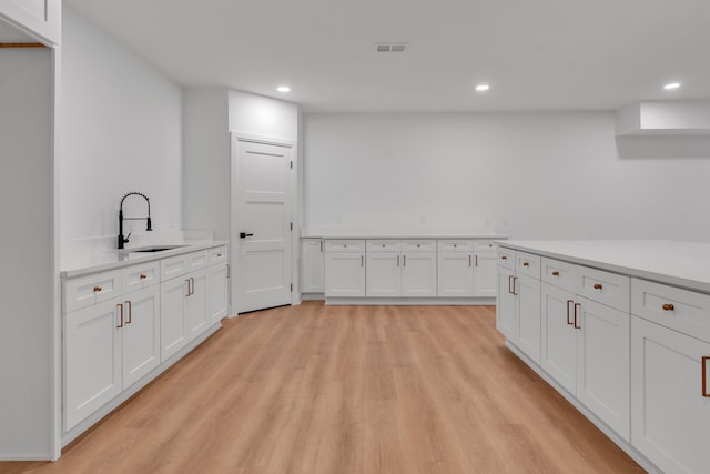 kitchen featuring light hardwood / wood-style flooring, white cabinets, and sink