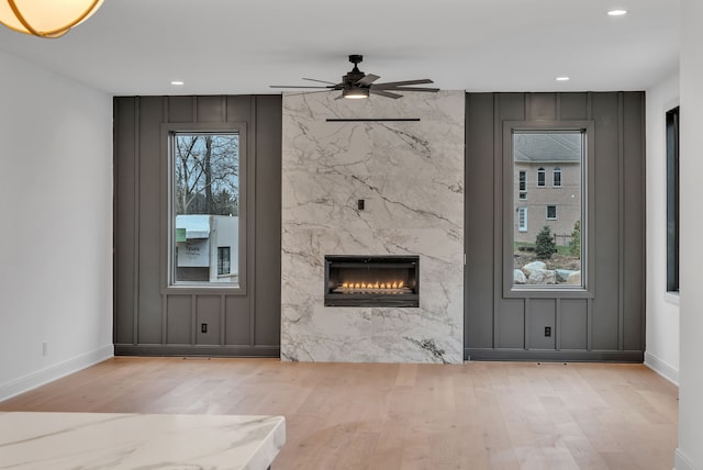 unfurnished living room featuring a fireplace, light hardwood / wood-style floors, and ceiling fan