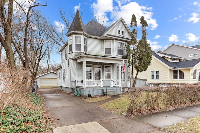 victorian house featuring covered porch, an outdoor structure, and a garage