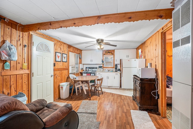 living room featuring light wood-type flooring, ceiling fan, and wooden walls