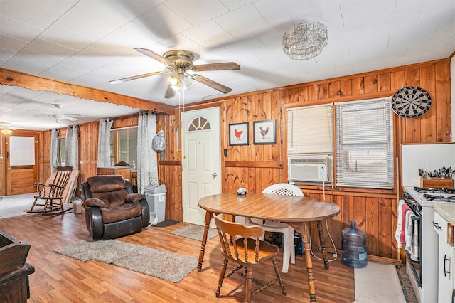 dining room with ceiling fan, light hardwood / wood-style floors, wooden walls, and cooling unit