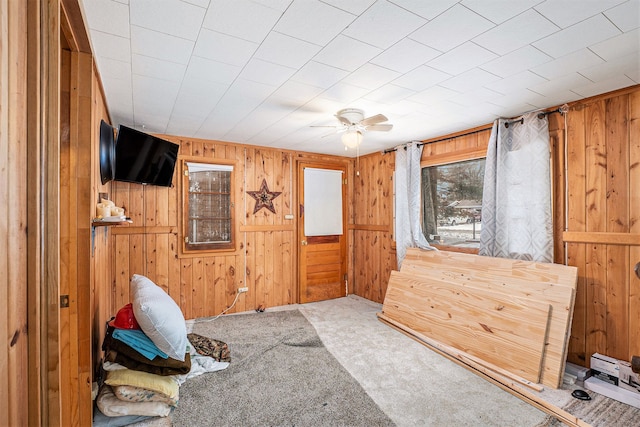 carpeted bedroom featuring ceiling fan and wood walls