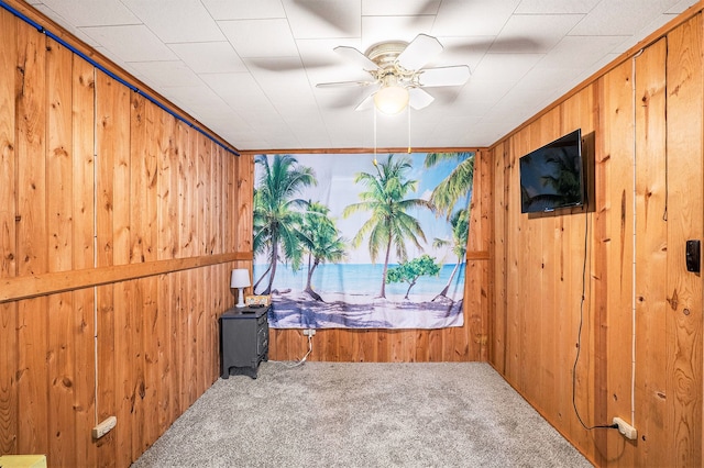 spare room featuring carpet, ceiling fan, and wooden walls