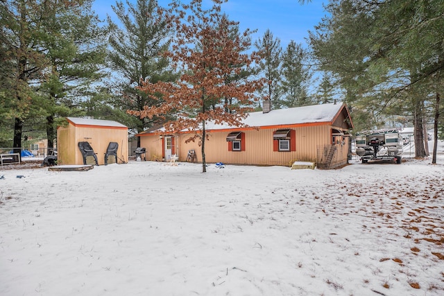 snow covered back of property with a storage shed