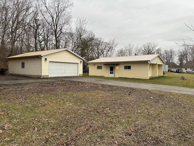 ranch-style home with a garage, an outdoor structure, and a front lawn