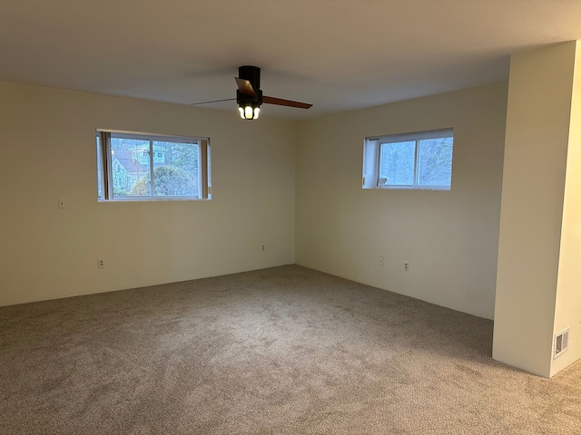 spare room with ceiling fan, a healthy amount of sunlight, and light carpet