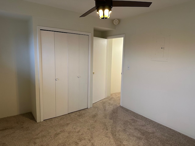 unfurnished bedroom featuring light colored carpet, a closet, ceiling fan, and electric panel