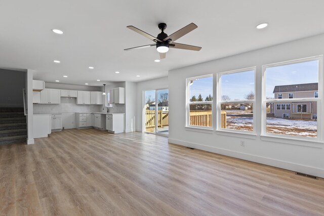 unfurnished living room featuring ceiling fan, light wood-type flooring, and sink