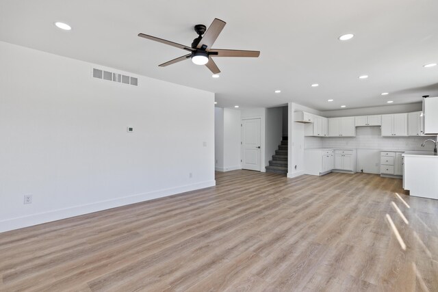 unfurnished living room featuring ceiling fan, light hardwood / wood-style floors, and sink