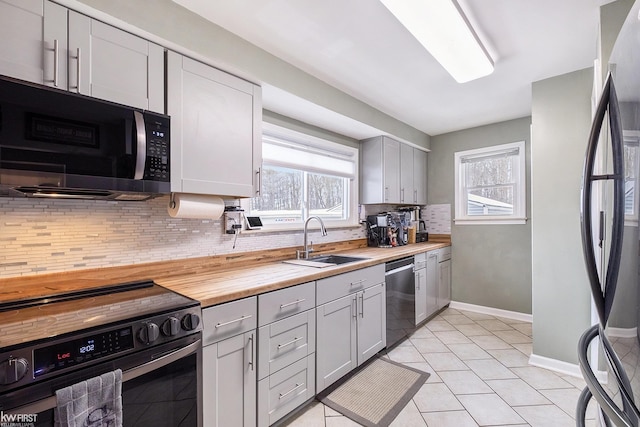 kitchen with stainless steel appliances, sink, light tile patterned floors, gray cabinets, and butcher block counters