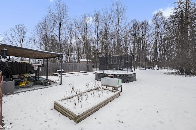 yard layered in snow featuring a trampoline