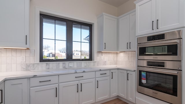 332 Arbor Ln, Saline, MI 48176 - kitchen with double oven, white cabinetry, tasteful backsplash, and light stone counters