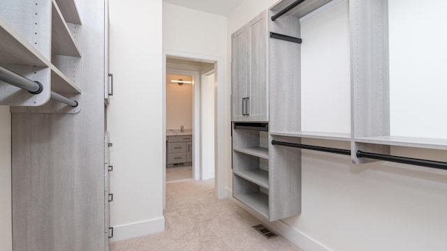 walk in closet with light carpet and sink