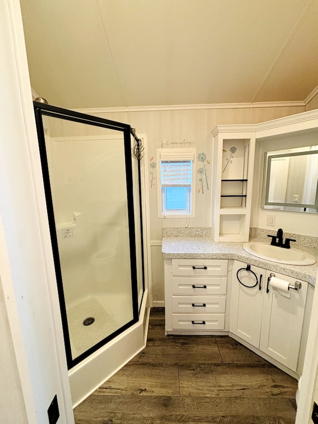 bathroom featuring hardwood / wood-style floors, vanity, vaulted ceiling, ornamental molding, and a shower with shower door