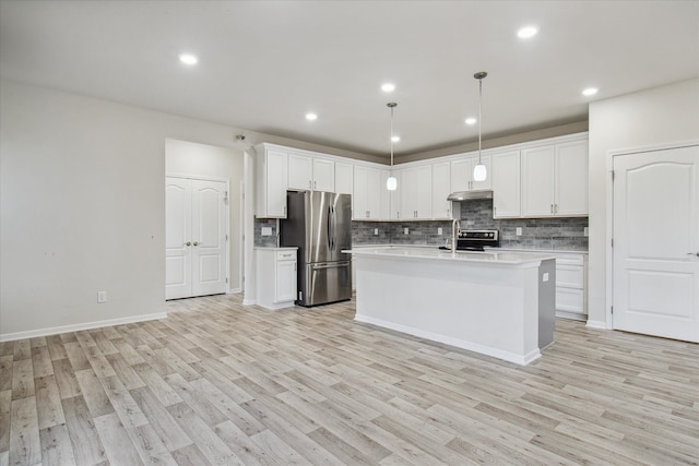 kitchen with white cabinetry, stainless steel appliances, pendant lighting, light hardwood / wood-style floors, and a center island with sink