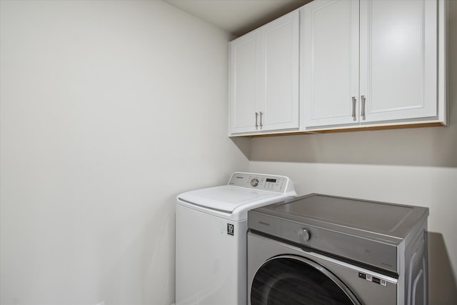 washroom featuring washing machine and dryer and cabinets